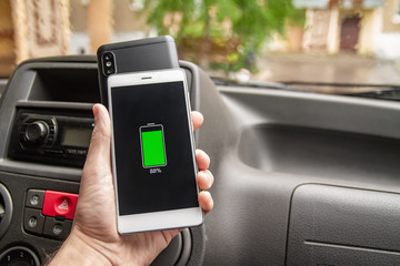Phone battery wireless charge sharing technology. Wireless charge sharing smartphone in the car in rainy weather