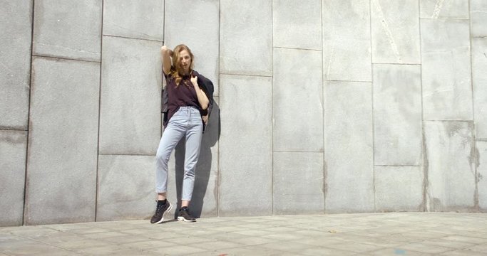 young fashion model is posing outdoors near tiled wall in sunny day