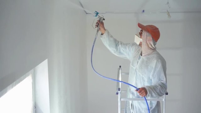 beauty slow motion. repair of the apartment - professional painter paints the walls with white paint spray gun