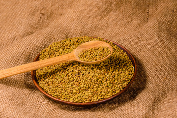 Ceramic plate and spoon with fenugreek seeds on a sackcloth