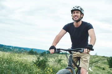 Attractive young man is cycling at the mountains. Cropped photo