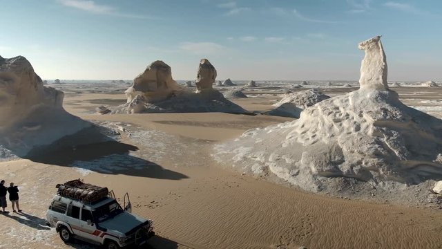 The White Desert & Black Desert in Egypt. Two people standing next to a 4 wheel drive in the desert