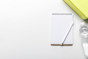 top view of water in bottle and blank notebook with pencil near box on white background