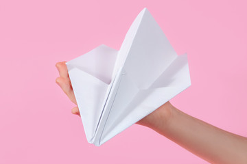 paper plane in the children's hand on a pink background. travel games with baby