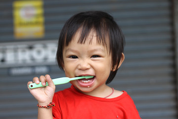 Happy Asian baby girl practice to brushing her teeth. A child aged of one year old. Healthy and kid concept.