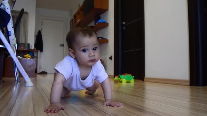 cute seven months old baby boy crawling on the floor and trying to stand up