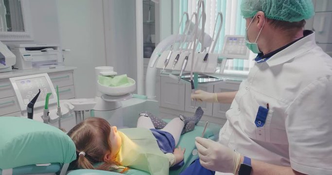 Dentist is repairing teeth of a little girl
