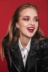Obraz na płótnie Canvas Image of gorgeous glamorous woman 20s with bright makeup wearing earrings and leather jacket smiling at camera
