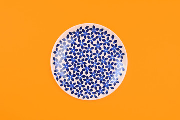 painted plate in blue flower on colour background .
