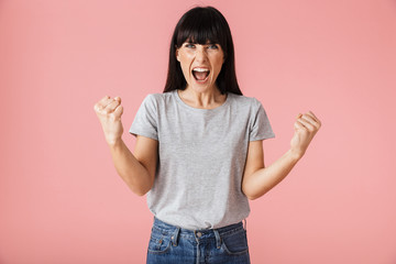 Happy excited woman posing isolated over light pink background wall make winner gesture.