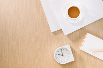 Flat lay of coffee cup, clock, pencil and a notebook.