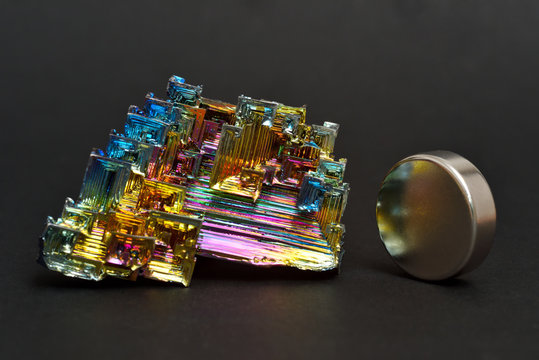 Bismuth crystals and a neodymium magnet on a dark background. This is the most strongly diamagnetic element and also the heaviest that is not radioactive.