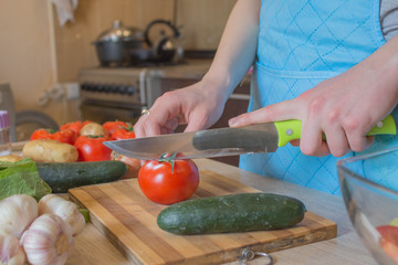 woman cooking healthy meal in the kitchen. Cooking healthy food at home. Woman in kitchen preparing vegetables. Chef cuts the vegetables into a meal