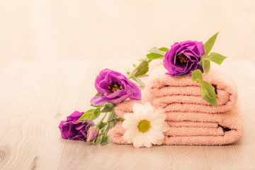Stack of soft terry towels with flowers on wooden boards