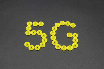 Many yellow plastic clothes buttons stitched into 5g numbers on black background