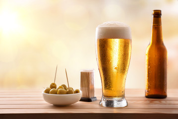 Appetizer with glass of fresh beer on wooden slatted table