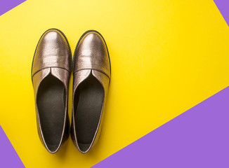 Pair of sparkly female shoes on yellow and purple background with copyspace.