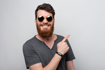 Portrait of smiling bearded man pointing away over white wall