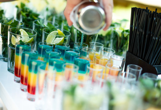 Bartenders Hands Making Cocktails And Shots On A Party Outside On A White Table.