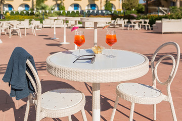 Two aperol spritz cocktails , chips and sunglasses on a table in an outdoor bar. Appetizer for two. Summer holidays