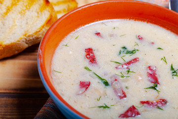 Spicy soup with sour cream, bread and spices on burned wooden table. Traditional rural dinner