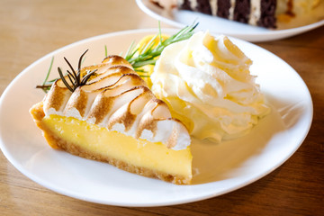 Lemon tart and whipped cream on a wooden table