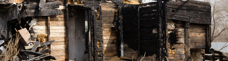 Brown and black burnt house of wooden planks with embossed texture without door and broken wall. damage to the building from fire without the possibility of its restoration