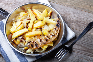 Delicious roast potatoes with onion and spices in a pan on kitchen towel on the old wooden table. Traditional rural dinner