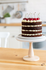 Summer dessert with cherries. Naked chocolate cake on the kitchen table. Holiday concept. Happy birthday card. Schwarzwalder Kirschtorte, Schwarzwald cake. Copy space