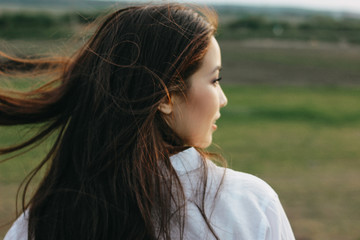 Close up portrait of beautiful carefree long hair girl in white clothes in the nature field, view...