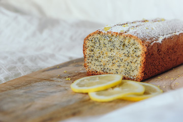 Cake with poppy seeds and lemon zest, sprinkled with powdered sugar. Cupcake with lemon on a wooden board