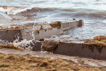 Destruction from the storm at sea. Broken concrete blocks of a building in the waves.
