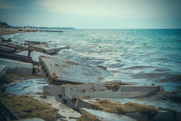 Destruction from the storm at sea. Broken concrete blocks of a building in the waves.