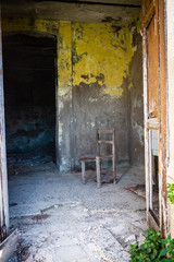 Old chair abandoned in a empty room. A glimpse of ghost town Alianello. Matera province, Italy