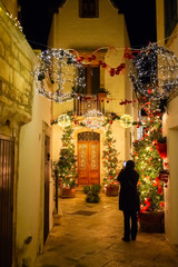 Girl takes a picture of Christmas decorated alley in Locorotondo at night. Apulia region, Italy