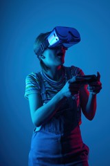 The game vr. The girl in the helmet and the controller plays a game with creative light. concept of cyber sports. games. viral reality © Anton