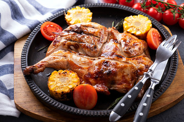 Roasted whole  chicken  with corn and tomatoes on frying pan.