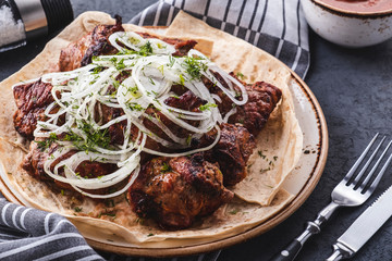Grilled pork kebab served with onion on a plate