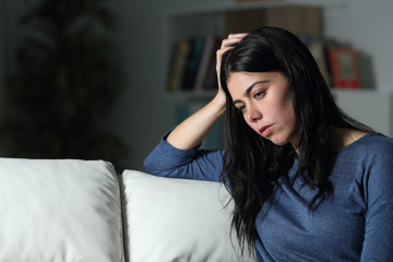 Sad woman thinking looking away in the night at home