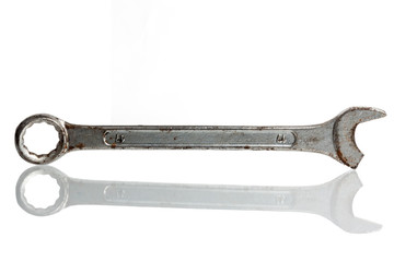 Old broken wrench on a white background with reflection.