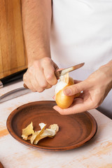Cook cleans onions with a knife close-up. Organic cooking concept.