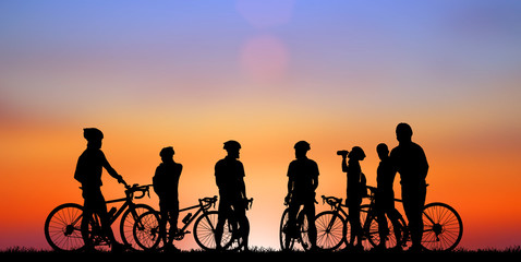 Silhouette group friend  and bike relaxing on blurry sunset background.