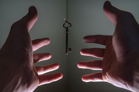 People hands reaching for vintage key hanging on a string. Busin