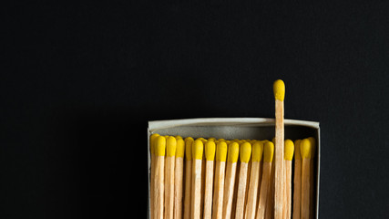Matches with yellow heads in a box, dark background. Macro photo
