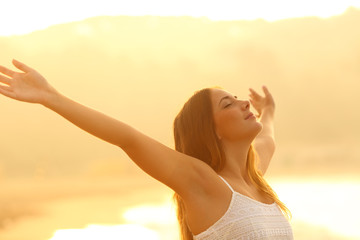 Relaxed woman stretching arms breathing fresh air at sunset