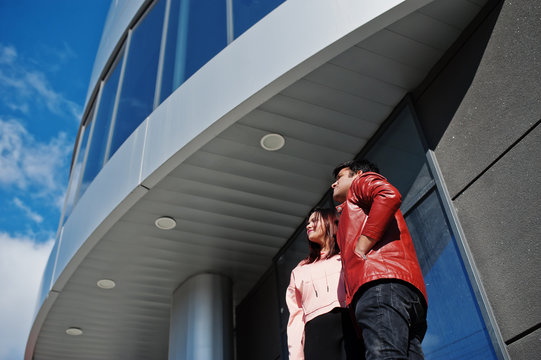 Asian couple standing together against new modern building and look at sky.