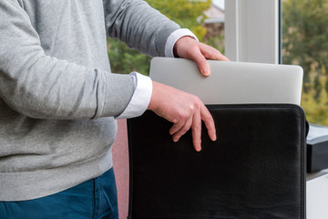 Young business man pulling out a laptop out of a leather case at