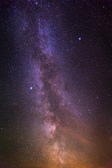 Night landscape with colorful milky way stars and yellow light.