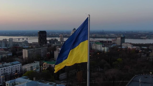Aerial footage of the flag of Ukraine with the city of Dnipro on the background