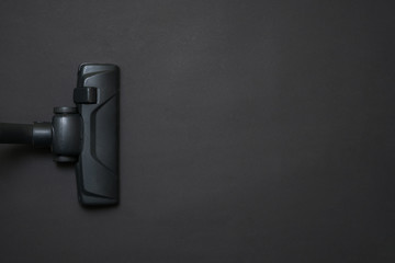 Dark head of a modern vacuum cleaner being used while vacuuming